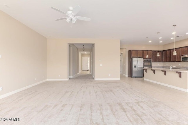 kitchen with appliances with stainless steel finishes, light carpet, and pendant lighting