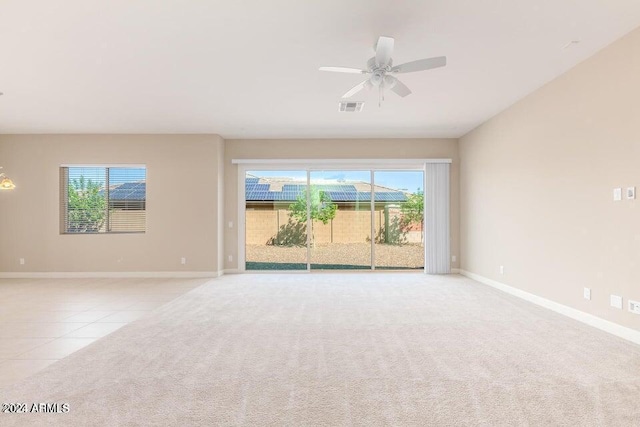 unfurnished room featuring light carpet, light tile patterned floors, baseboards, visible vents, and ceiling fan