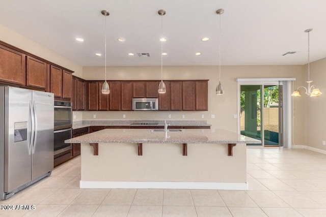 kitchen featuring pendant lighting, stainless steel appliances, a kitchen island with sink, and light tile patterned floors