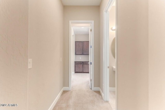 corridor featuring light carpet and baseboards