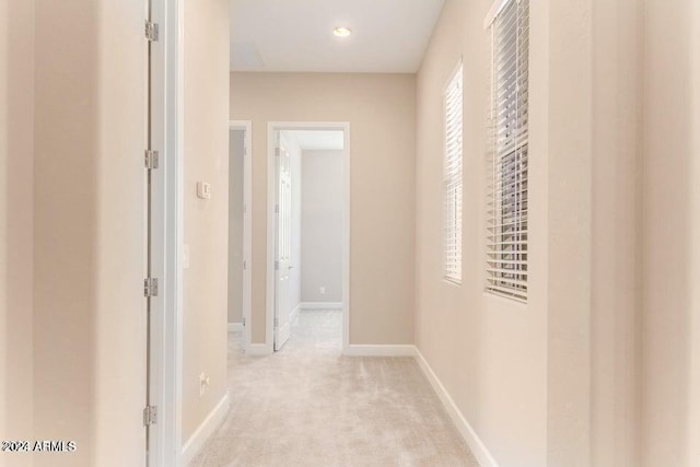 hall with baseboards and light colored carpet