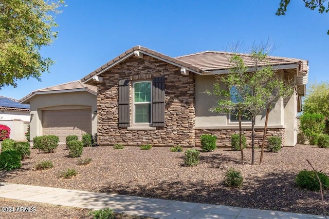 view of front of property with an attached garage, stone siding, a tiled roof, and stucco siding