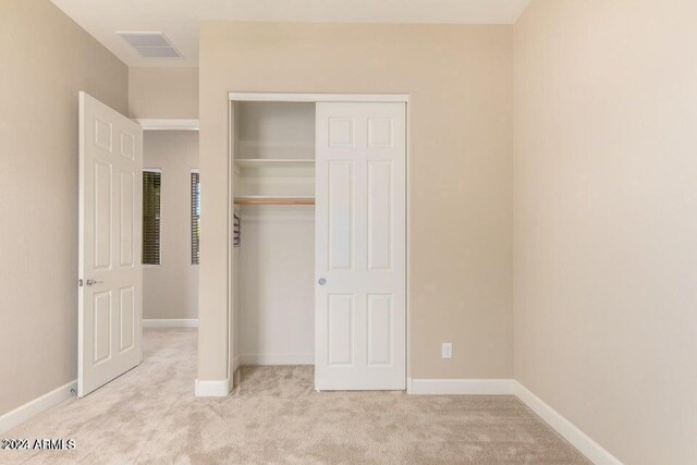 unfurnished bedroom with light carpet and a closet