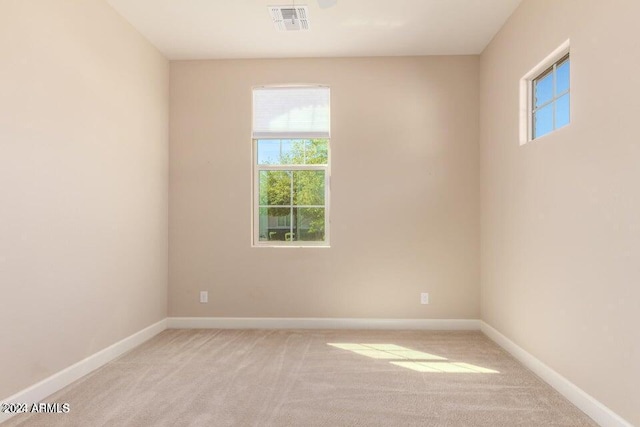 spare room featuring baseboards, visible vents, and light colored carpet