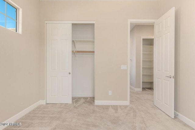 unfurnished bedroom featuring a closet, light colored carpet, and baseboards