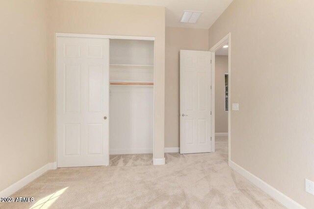 unfurnished bedroom with light carpet and a closet