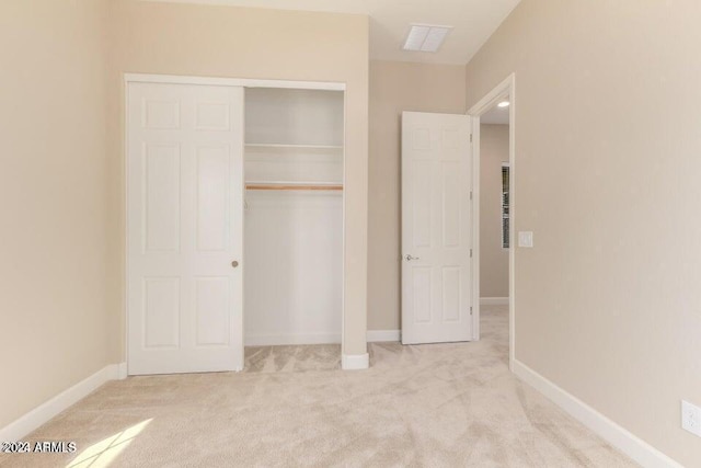 unfurnished bedroom with a closet, light carpet, visible vents, and baseboards