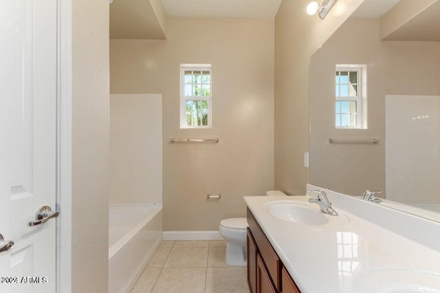 bathroom featuring a bathing tub, toilet, a sink, baseboards, and tile patterned floors