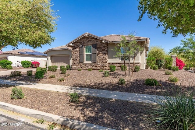 view of front of house featuring a garage, driveway, stone siding, a tile roof, and stucco siding