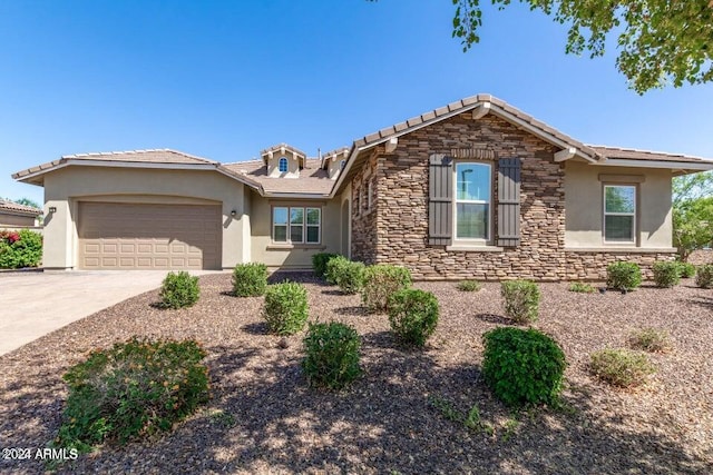 single story home with a garage, stone siding, concrete driveway, and stucco siding