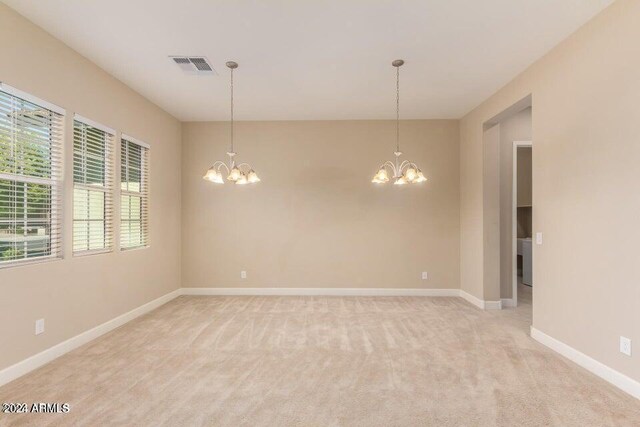 unfurnished room with light carpet and a chandelier