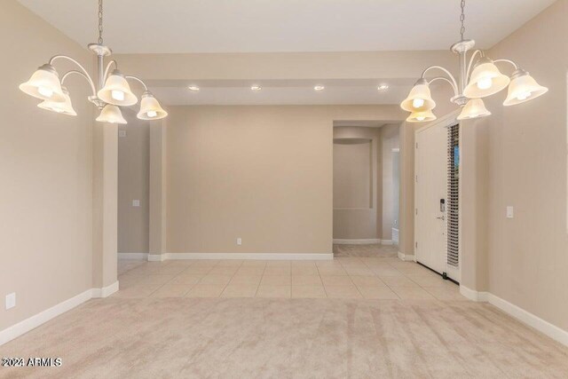 carpeted spare room featuring a chandelier