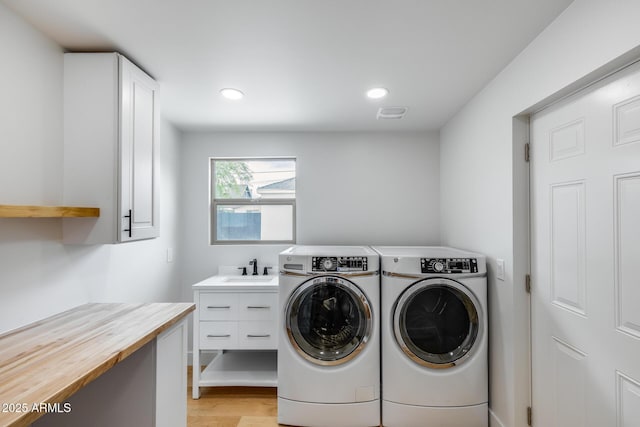 clothes washing area featuring recessed lighting, a sink, light wood finished floors, cabinet space, and washer and clothes dryer