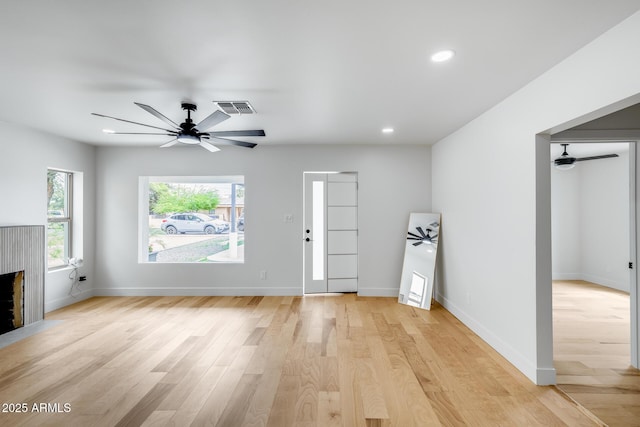 unfurnished living room with visible vents, ceiling fan, and light wood-type flooring