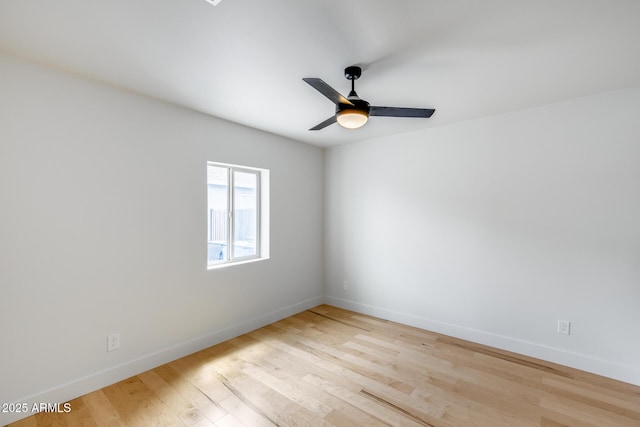 spare room with baseboards, light wood finished floors, and a ceiling fan