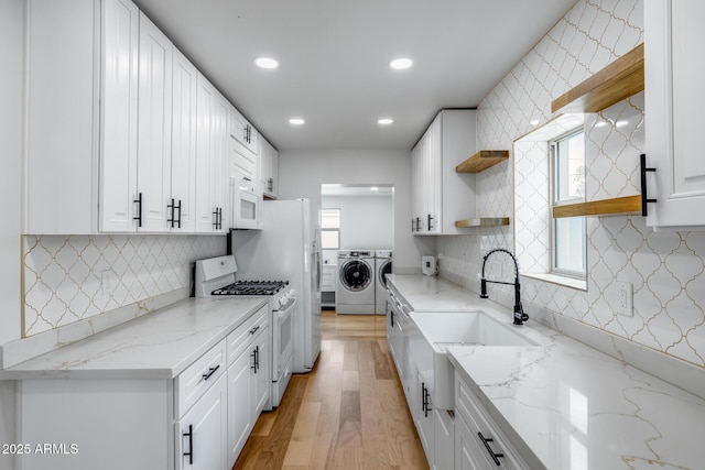 kitchen featuring white appliances, white cabinetry, open shelves, recessed lighting, and washing machine and clothes dryer