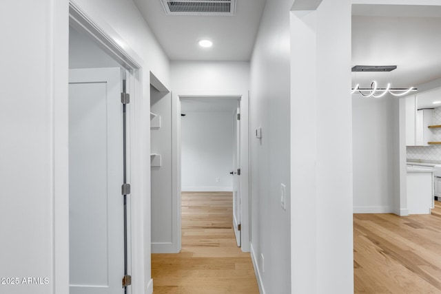 corridor featuring light wood-style flooring, baseboards, visible vents, and recessed lighting