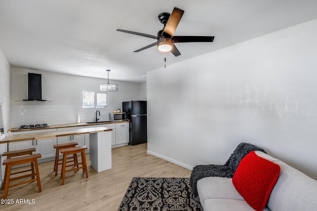 living room with light wood-style floors, baseboards, and a ceiling fan