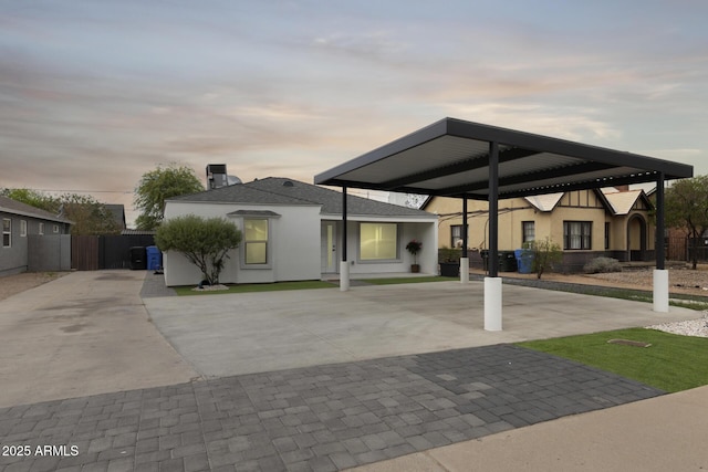 view of front of home with fence, driveway, a carport, and stucco siding