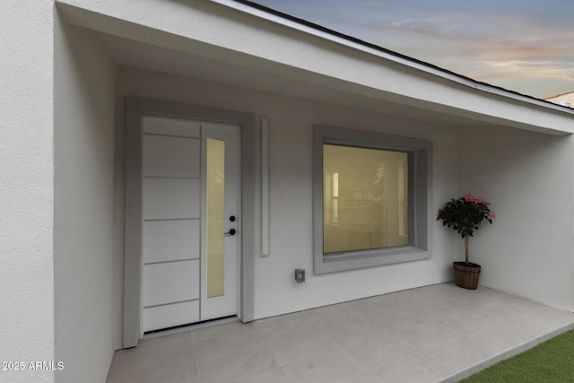 doorway to property featuring stucco siding