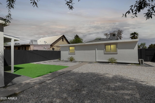 back of house at dusk with fence and stucco siding