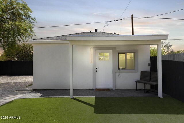 outdoor structure at dusk with a yard and fence