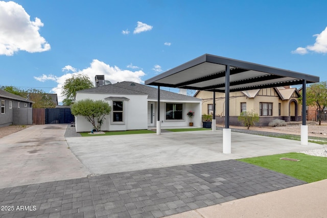view of front of home with concrete driveway, a carport, stucco siding, and fence