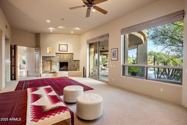 carpeted living room featuring ceiling fan and a fireplace