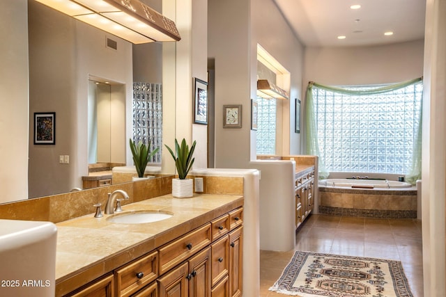 bathroom with tile patterned floors, vanity, and tiled tub