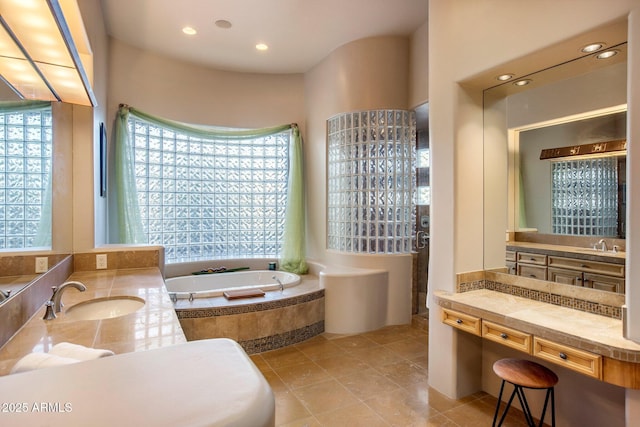 bathroom with tile patterned flooring, vanity, and tiled bath