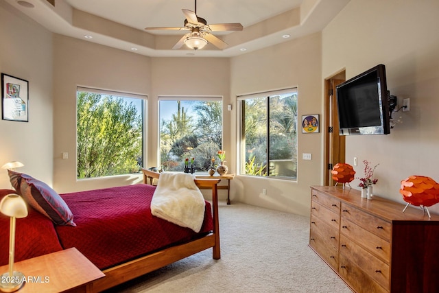 carpeted bedroom with ceiling fan and a tray ceiling