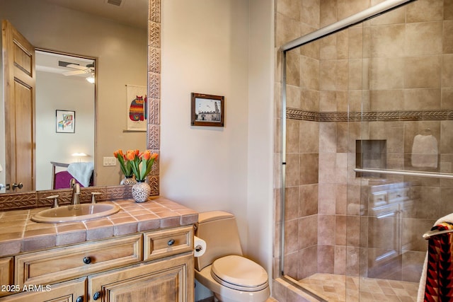 bathroom with a shower with door, vanity, ceiling fan, and toilet