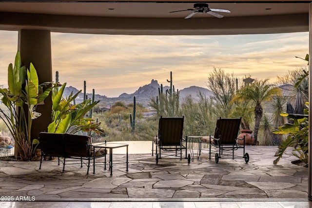 patio terrace at dusk with ceiling fan and a mountain view