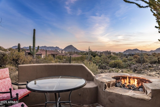 patio terrace at dusk featuring a mountain view and a fire pit