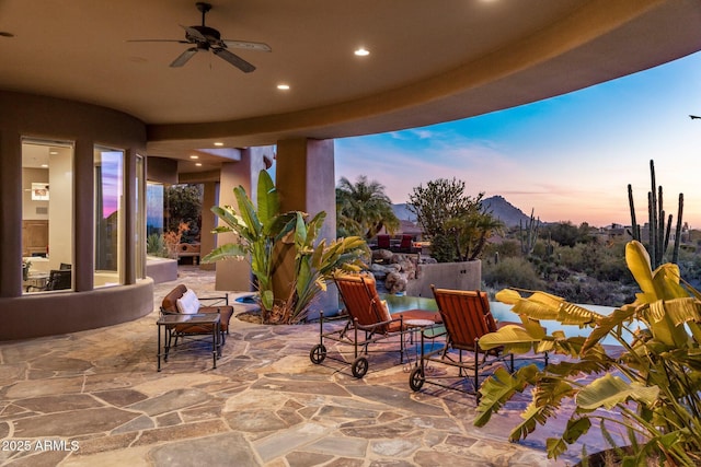 patio terrace at dusk with a mountain view and ceiling fan