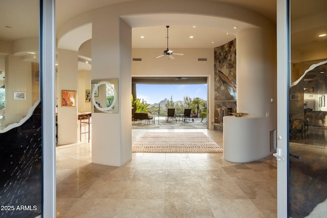 doorway featuring ceiling fan and a high ceiling