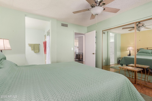 bedroom featuring a closet, a textured ceiling, ceiling fan, and parquet floors