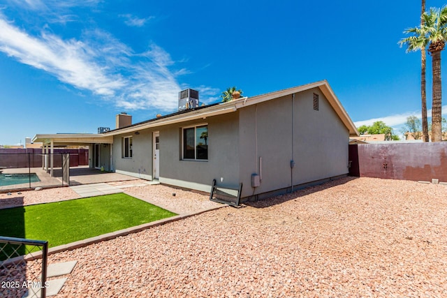 back of house with a patio, a fenced backyard, stucco siding, and a chimney