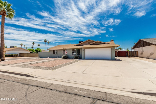 ranch-style house featuring driveway, a chimney, fence, an attached garage, and stucco siding