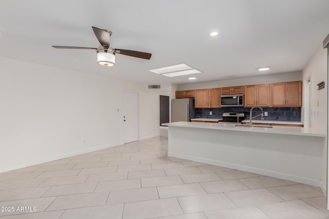 kitchen featuring appliances with stainless steel finishes, a sink, light countertops, recessed lighting, and decorative backsplash