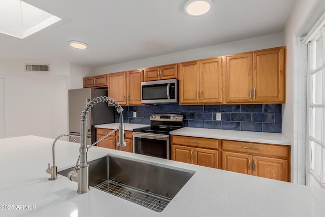 kitchen featuring visible vents, decorative backsplash, light countertops, a sink, and stainless steel appliances