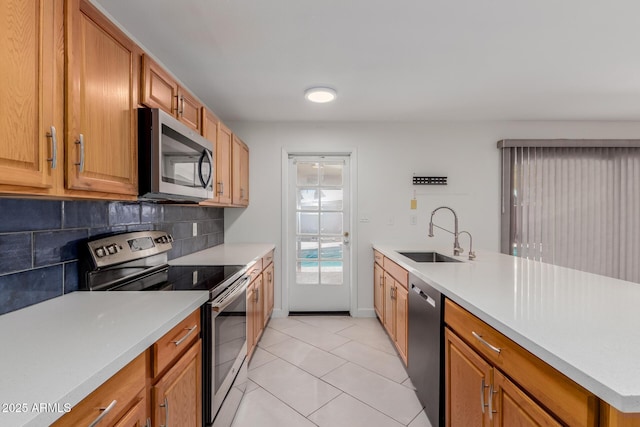kitchen featuring light countertops, a sink, backsplash, light tile patterned floors, and stainless steel appliances