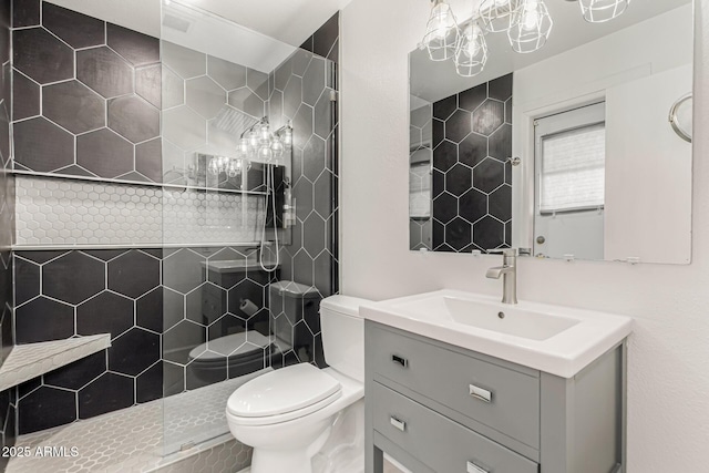 full bath with vanity, a tile shower, and toilet