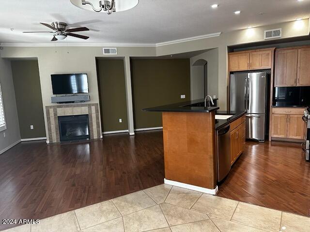 kitchen featuring a kitchen island with sink, ornamental molding, stainless steel appliances, and ceiling fan