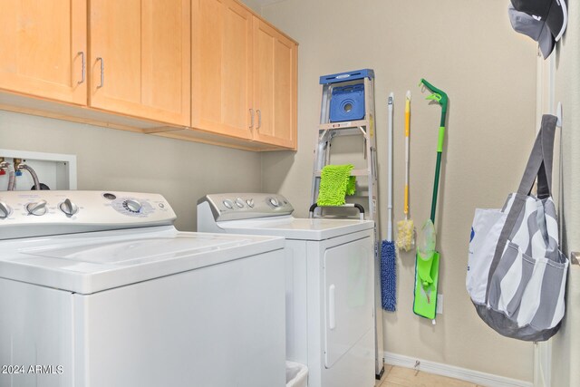 clothes washing area featuring cabinets and separate washer and dryer