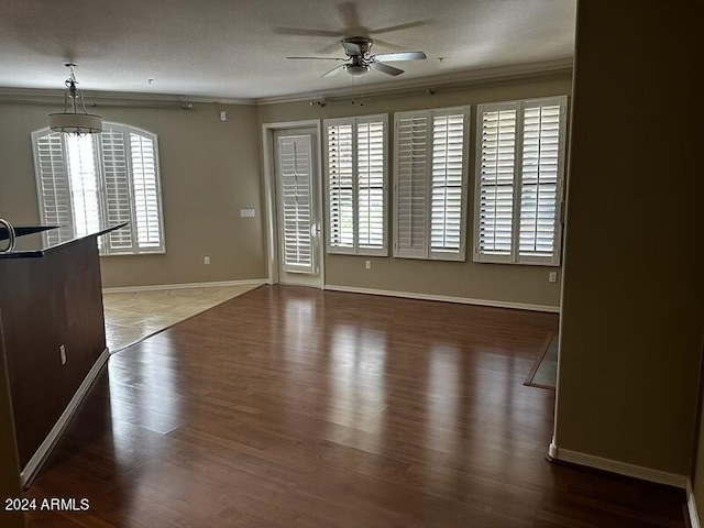 unfurnished room featuring a textured ceiling, crown molding, hardwood / wood-style floors, and ceiling fan with notable chandelier