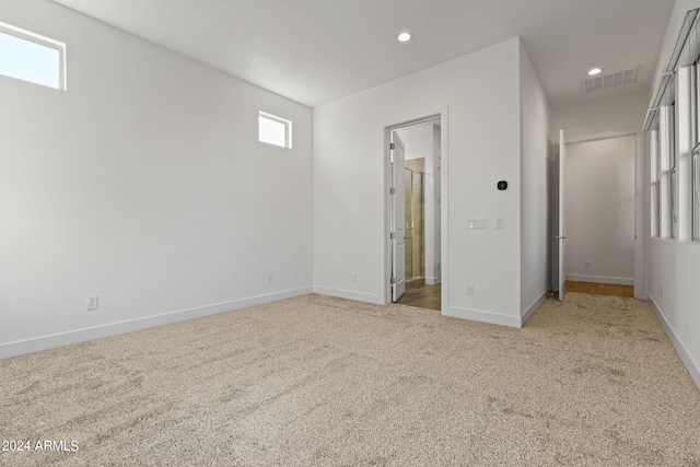 unfurnished bedroom with connected bathroom and light colored carpet