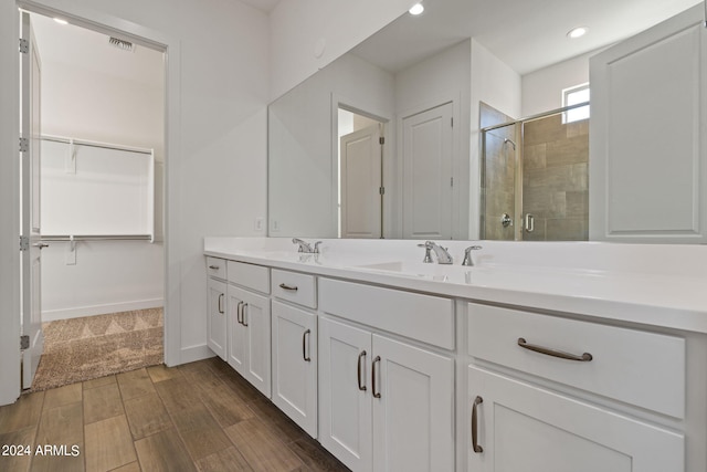 bathroom with hardwood / wood-style floors, a shower with shower door, and vanity