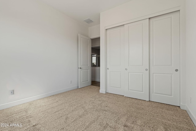 unfurnished bedroom with a closet and light carpet