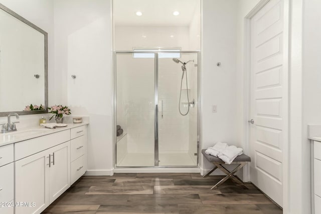 bathroom with hardwood / wood-style floors, vanity, and a shower with door